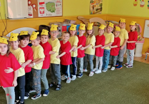 Dzieci stoją w szeregu, naprzemian w czerwonych i żółtych koszulkach